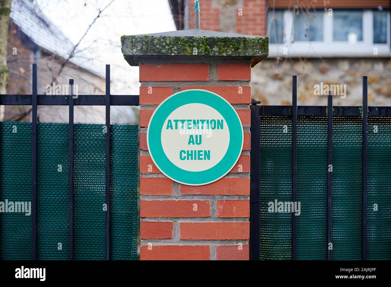 "L'attenzione au chien' ('Attenzione al cane') segno sulla recinzione in mattoni post Foto Stock