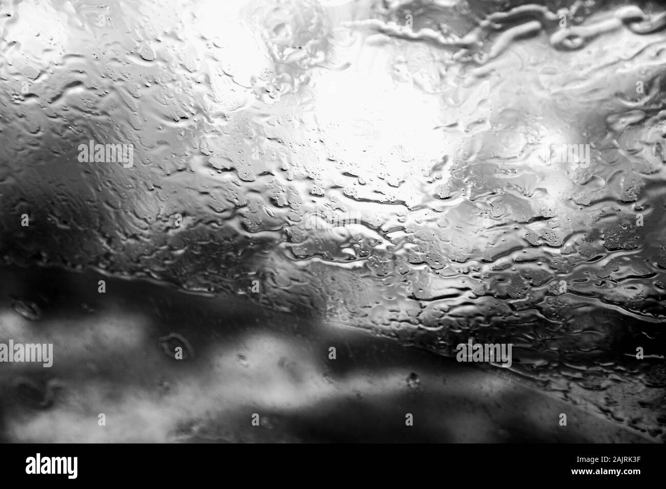 Finestrino dell'auto con gocce di pioggia. Guida sotto la pioggia. Condizioni meteo di fondo. Vetro piovoso. Foto Stock