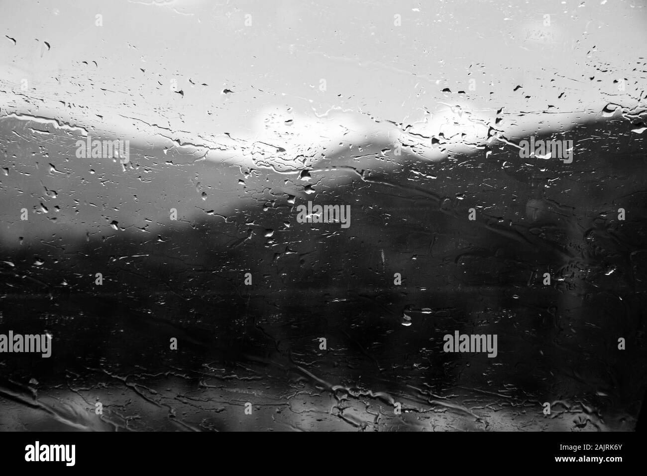 Finestrino dell'auto con gocce di pioggia. Guida sotto la pioggia. Condizioni meteo di fondo. Vetro piovoso. Foto Stock