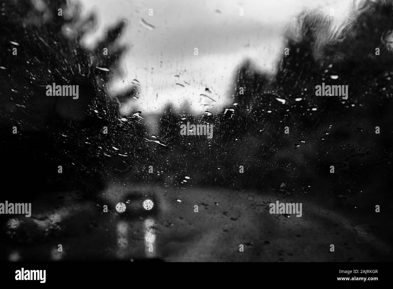 Finestrino dell'auto con gocce di pioggia. Guida sotto la pioggia. Condizioni meteo di fondo. Vetro piovoso. Foto Stock