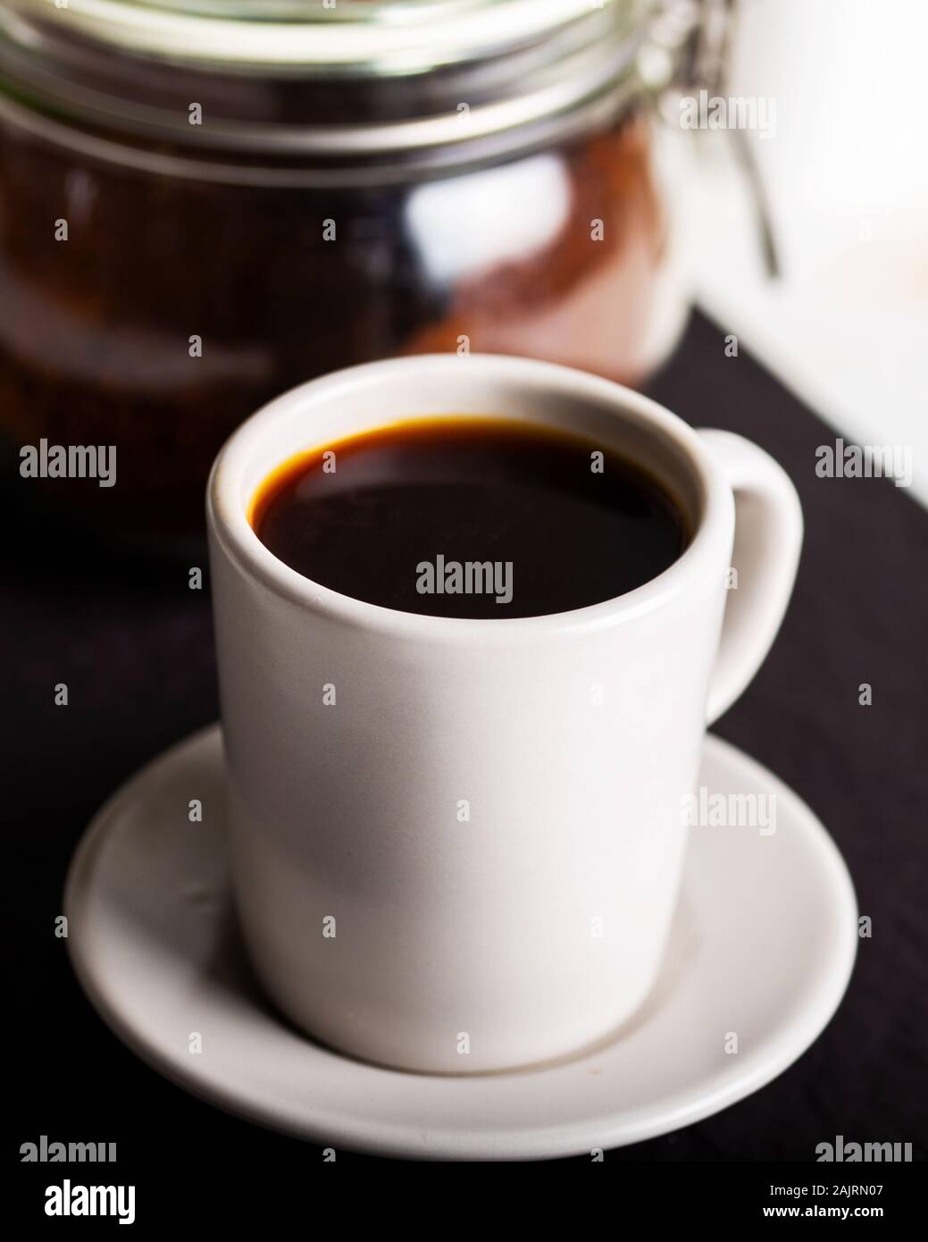 Una tazza di caffè e un cucchiaio per versare la polvere di caffè Foto Stock