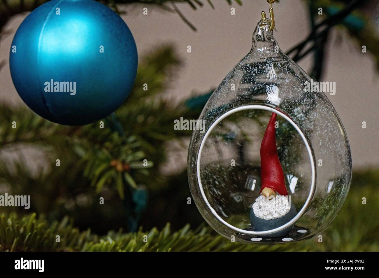 Le decorazioni di Natale, blu ninnolo e Santa's Elf in una sfera, appeso a un albero Foto Stock
