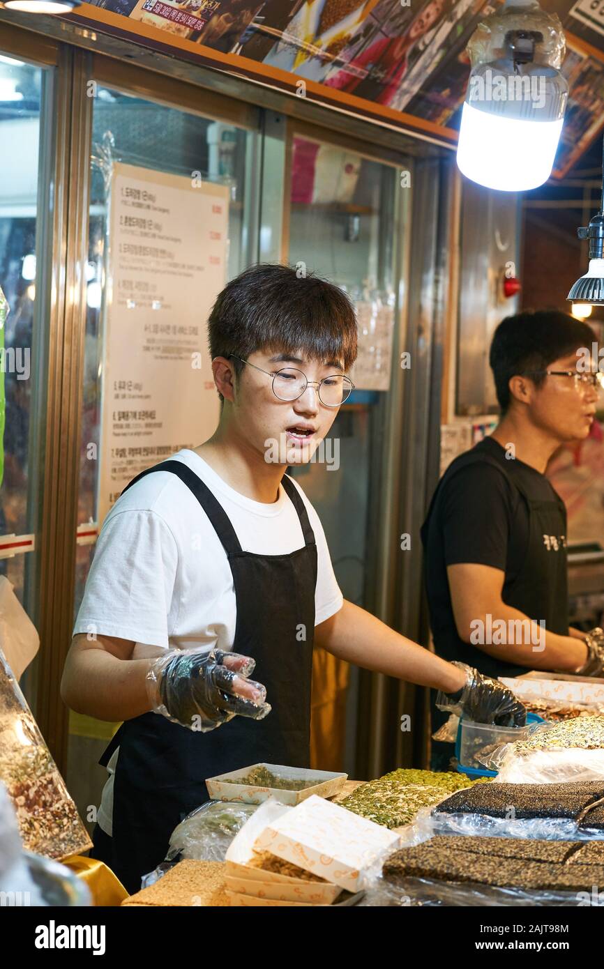 Il giovane chef maschile prepara il cibo per la vendita al mercato Gwangjang di Seoul, Corea del Sud. Foto Stock