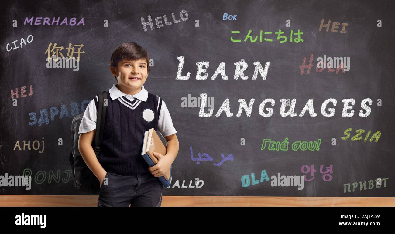 Scolaro di fronte a una lavagna con ciao scritte in lingue diverse e testo imparare le lingue Foto Stock