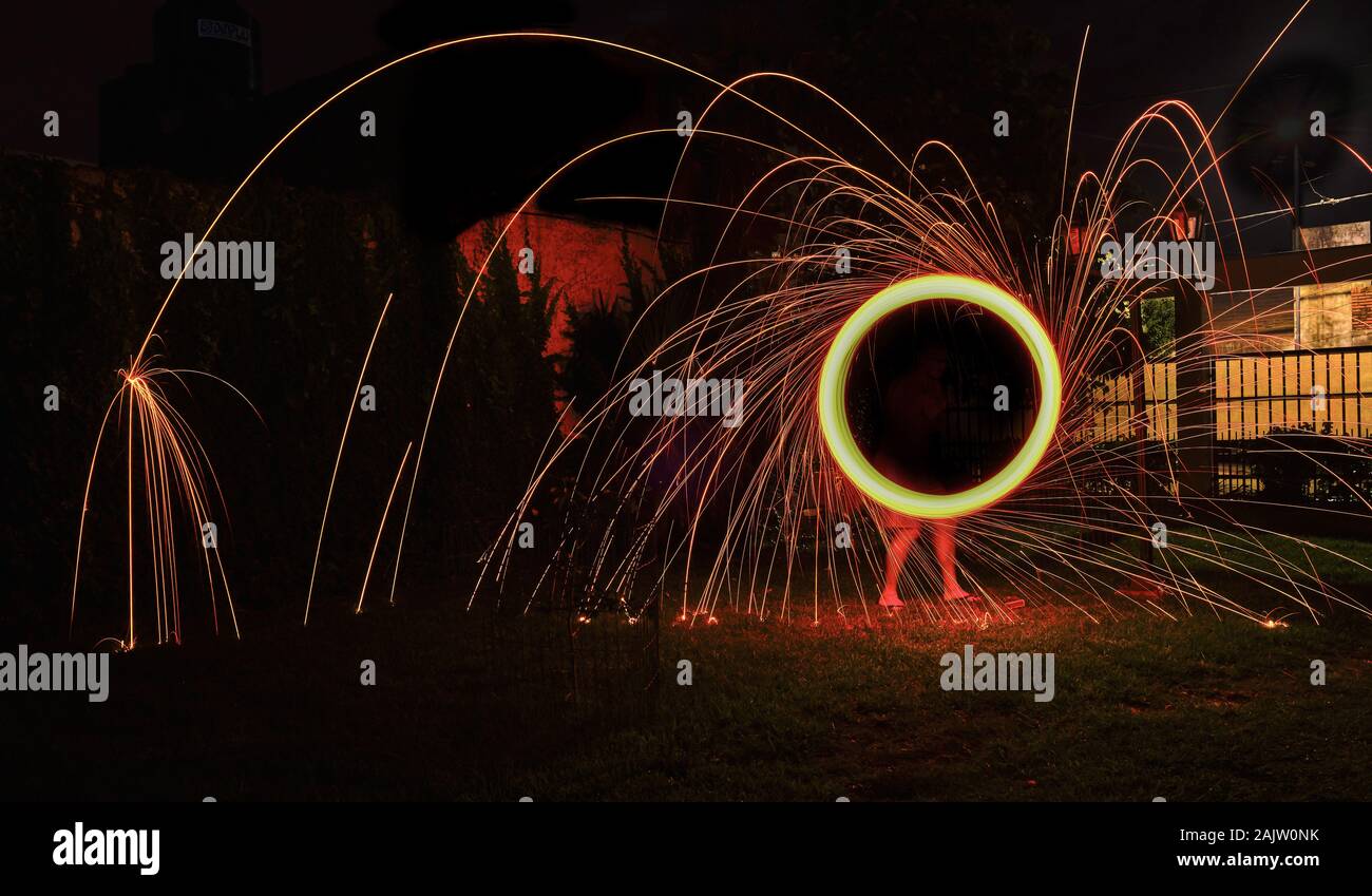 Una lunga esposizione della fotografia di una lana di acciaio sul fuoco andando in cerchi e caduta di ferro sul fuoco come una doccia Foto Stock