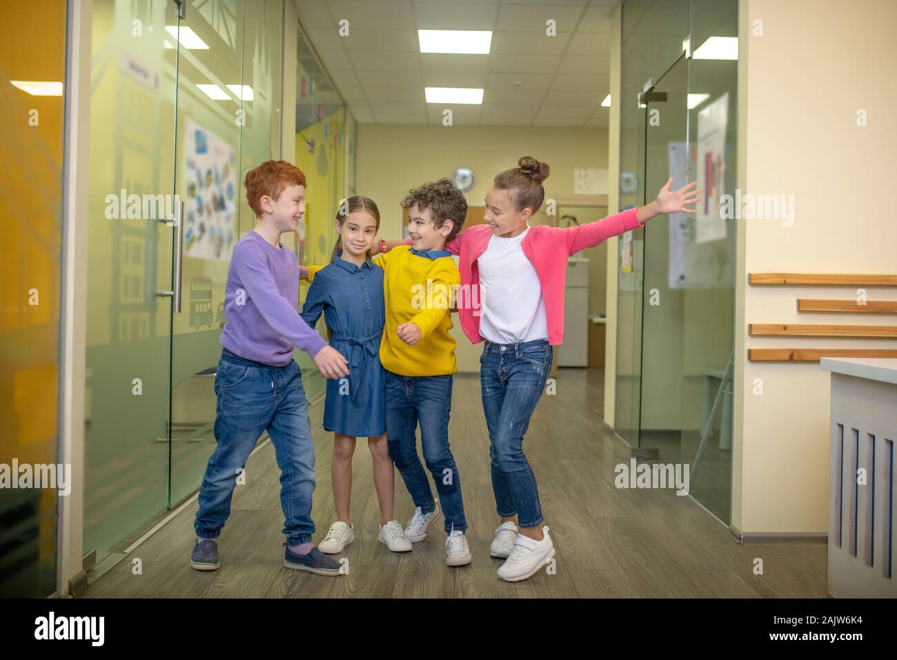 Un gruppo di bambini che sono lieto di vedere il loro compagno di classe Foto Stock