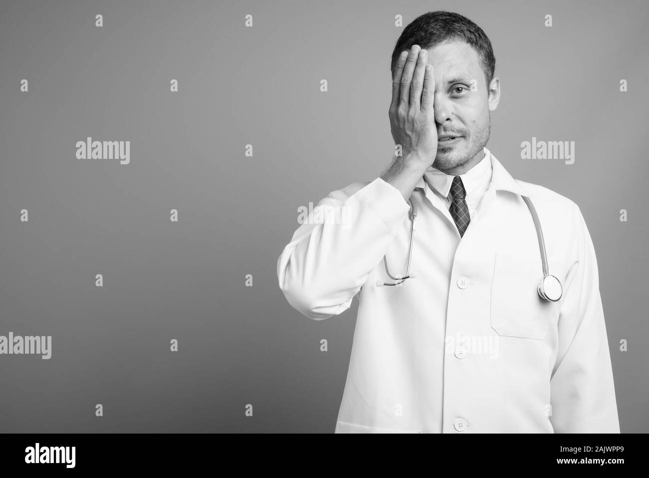 Ritratto di uomo bello medico contro uno sfondo grigio Foto Stock