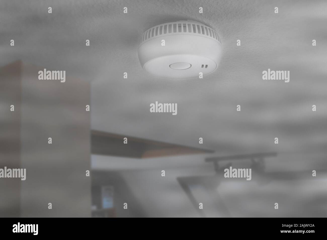 Domestico allarme fumo / alimentato a batteria per il rilevatore di fumo sul soffitto della camera riempita con fumo dal fuoco a casa Foto Stock