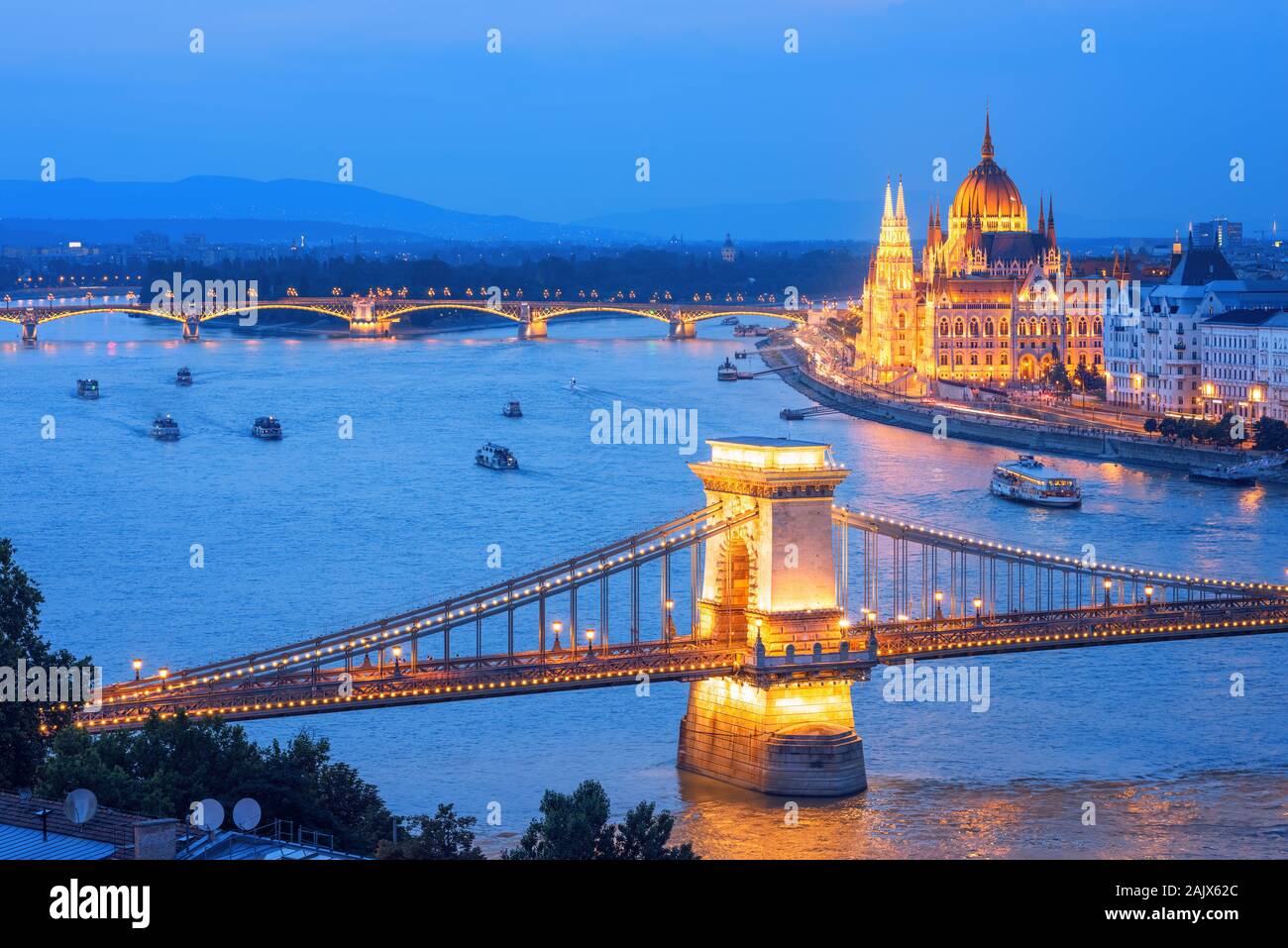 La città di Budapest, Ungheria, le barche turistiche crociera sul fiume Danubio lungo il ponte delle catene e il palazzo del Parlamento su una serata blu Foto Stock