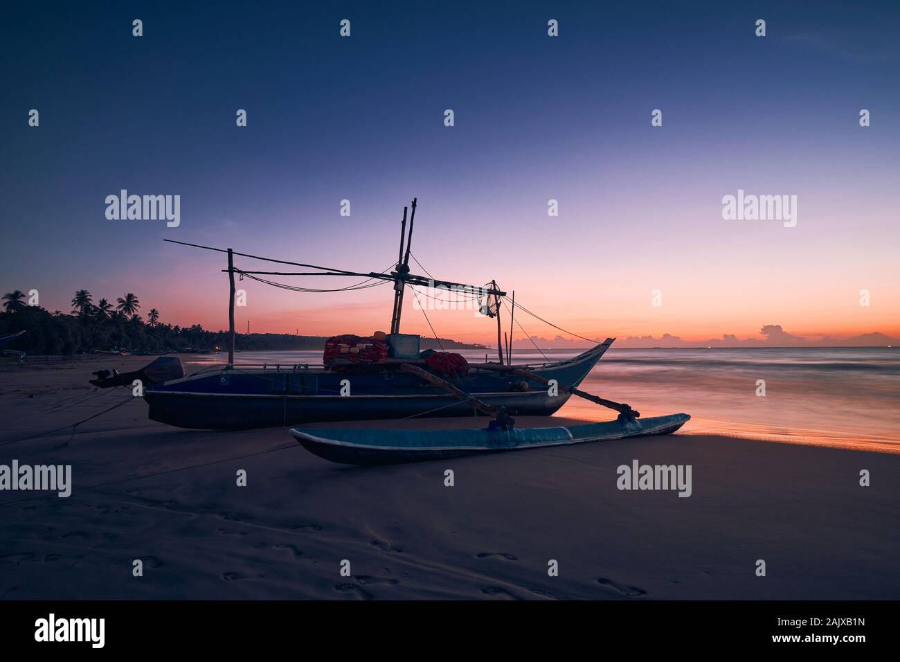 Seascape all alba colorata. Barche da pesca sulla spiaggia di sabbia, Sri Lanka Foto Stock