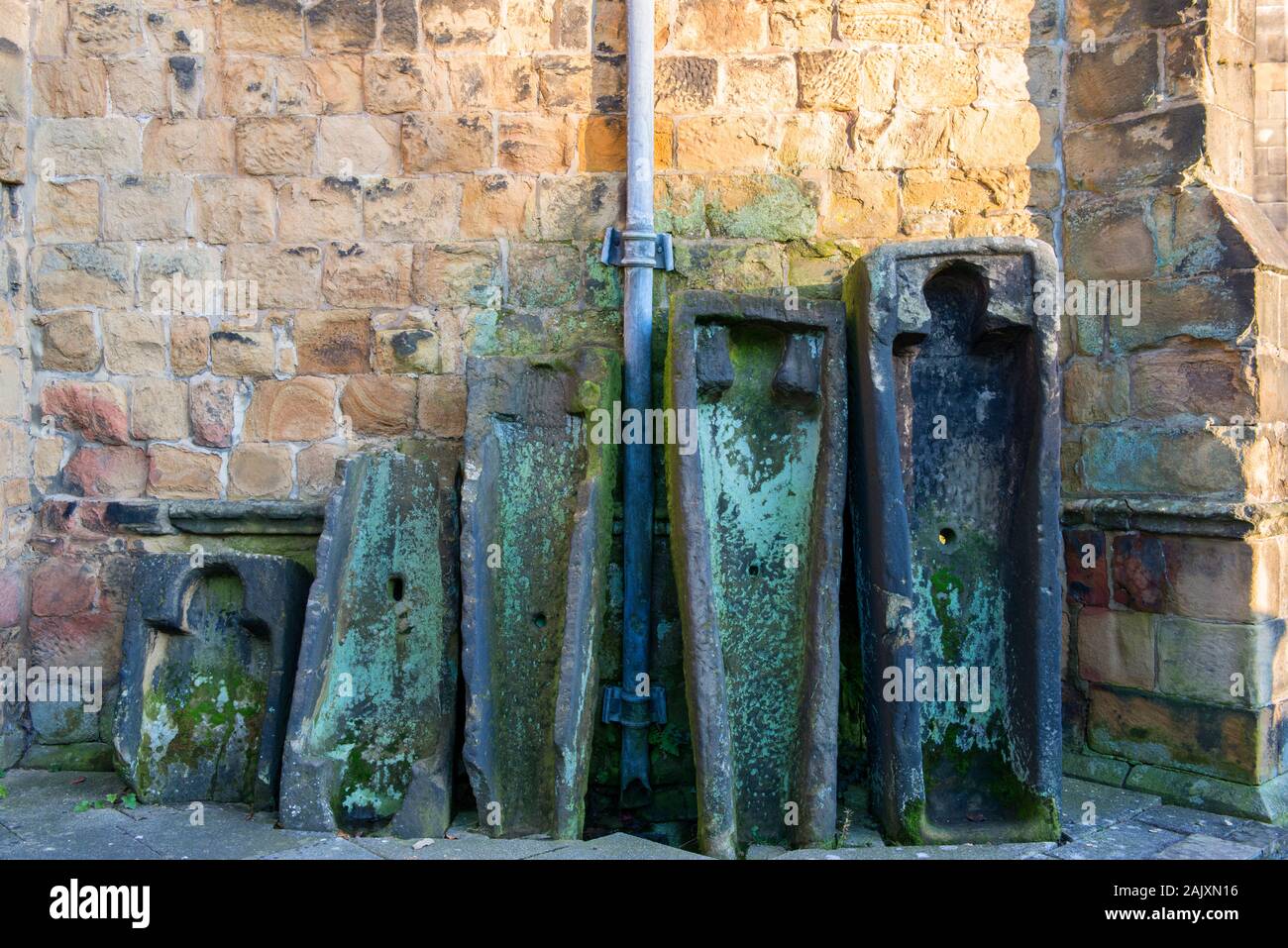 Antico in pietra bare appoggiata contro il muro di Bakewell Chiesa Parrocchiale Foto Stock