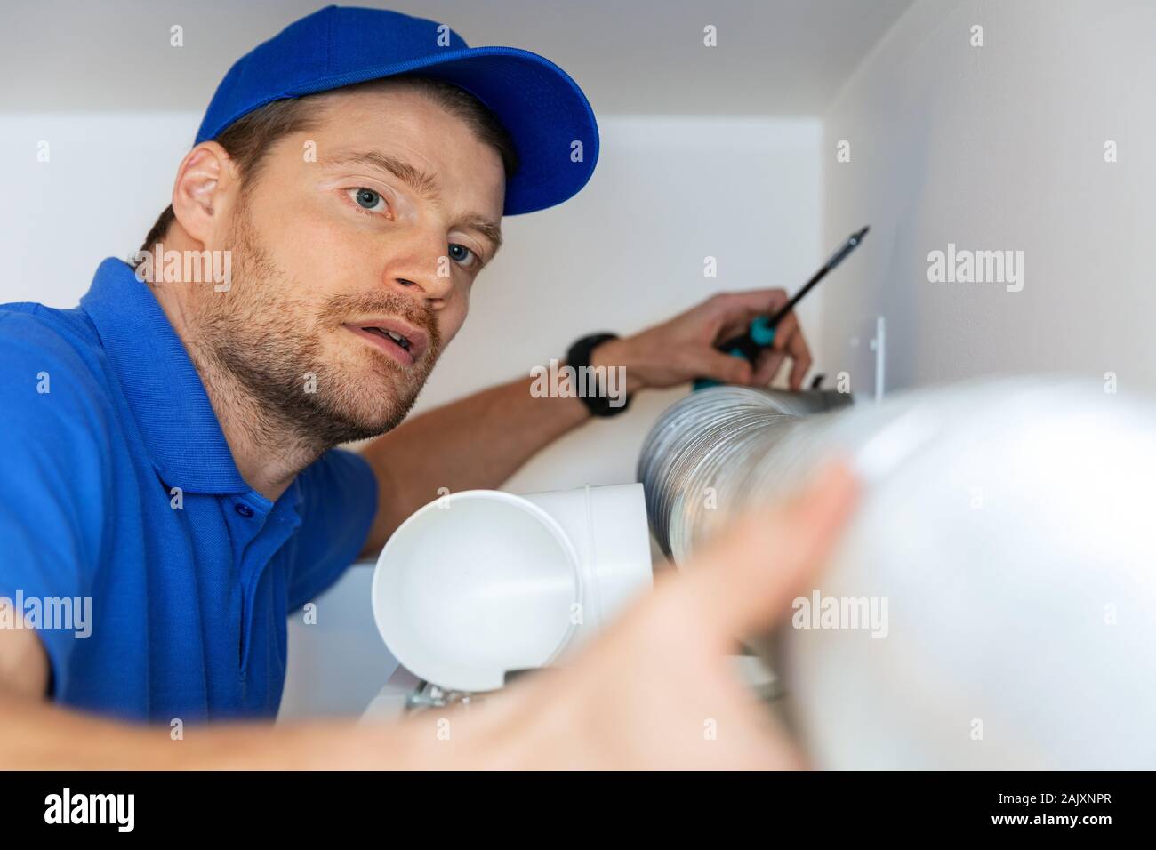 Tecnico di impianti di termoventilazione installazione flessibile tubo in alluminio per alloggiare il sistema di ventilazione Foto Stock