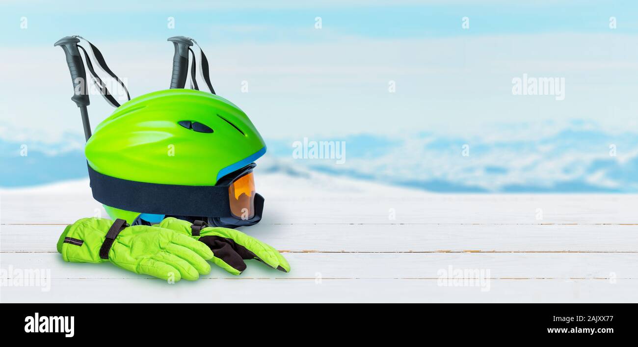 Attrezzatura da sci su una bianca tavolo in legno. Casco, guanti, occhiali nad poli. Copia spazio accanto. Cime innevate sullo sfondo Foto Stock