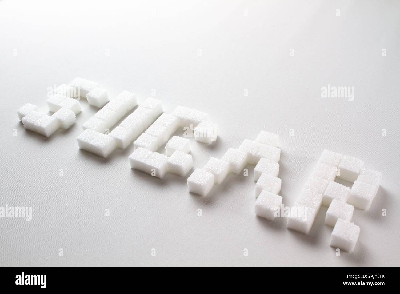 " Zucchero " scritto con pixel art lettere fatte di zollette di zucchero su sfondo bianco Foto Stock