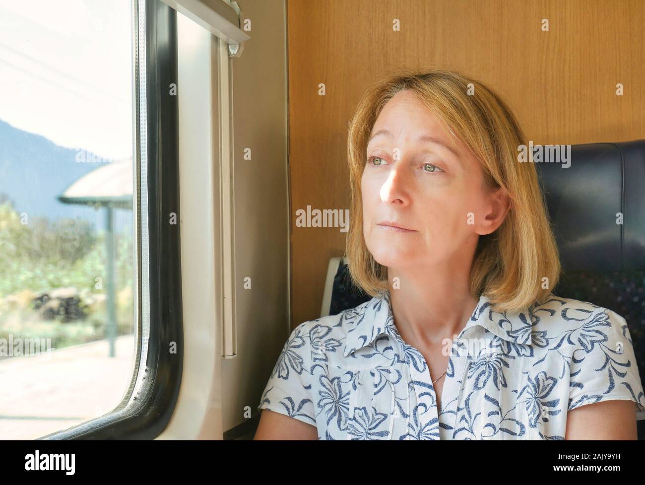 Una sola donna pensieroso nel pensiero, viaggiare su un treno, guardando attraverso una finestra durante il giorno. Foto Stock