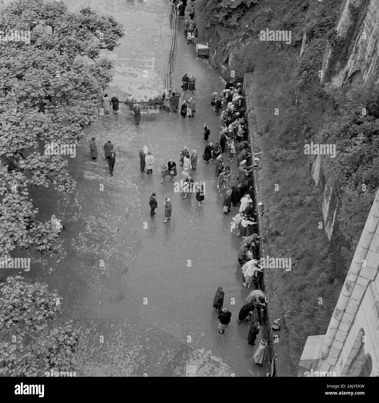 1950s, veduta storica e sovrana della gente al famoso santuario di Lourdes, in Francia, dove la Vergine Maria apparve a Maria Bernada Sobiros. Le acque del santuario (grotta) sono una grande attrazione per i molti che fanno il pellegrinaggio alla città Santa e che vogliono gioire nella loro fede cattolica. Foto Stock