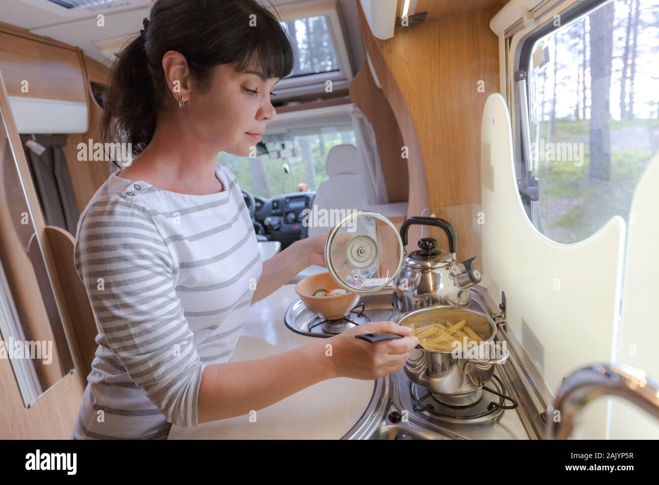 Donna cucinare in camper, camper RV interni. Vacanza per la famiglia in viaggio, viaggio vacanza in camper, caravan auto vacanza. Foto Stock