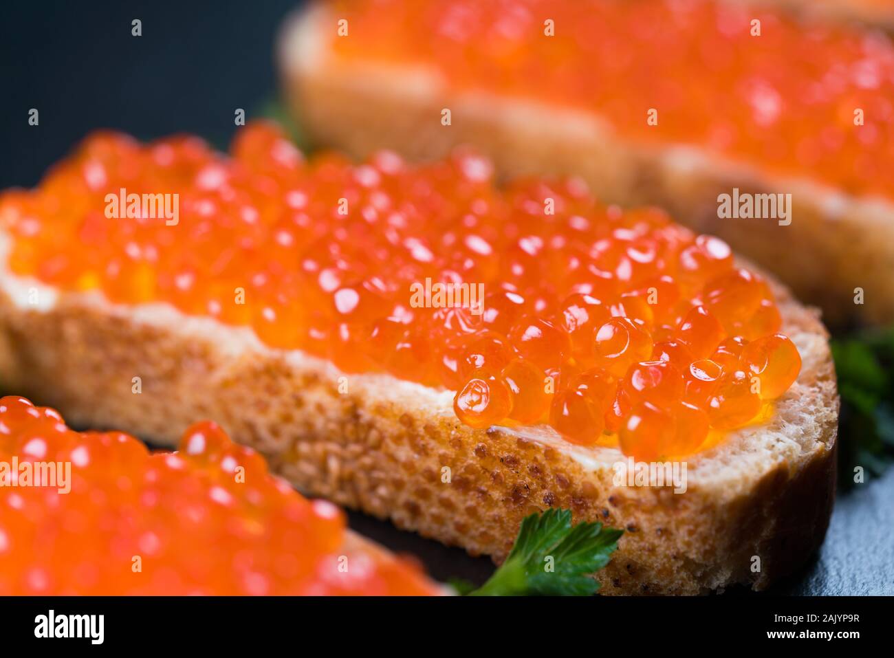 Panini con caviale rosso scuro su sfondo di pietra Foto Stock