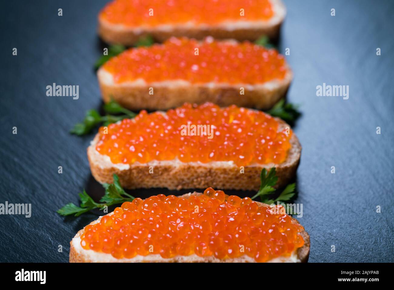 Panini con caviale rosso scuro su sfondo di pietra Foto Stock