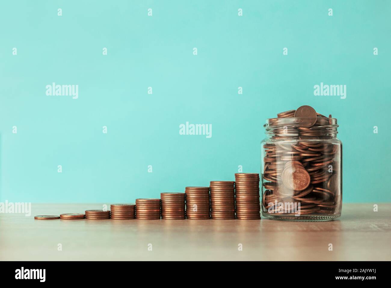 Foto di stock di una scala ascendente di monete su uno sfondo blu con un vaso pieno di monete Foto Stock
