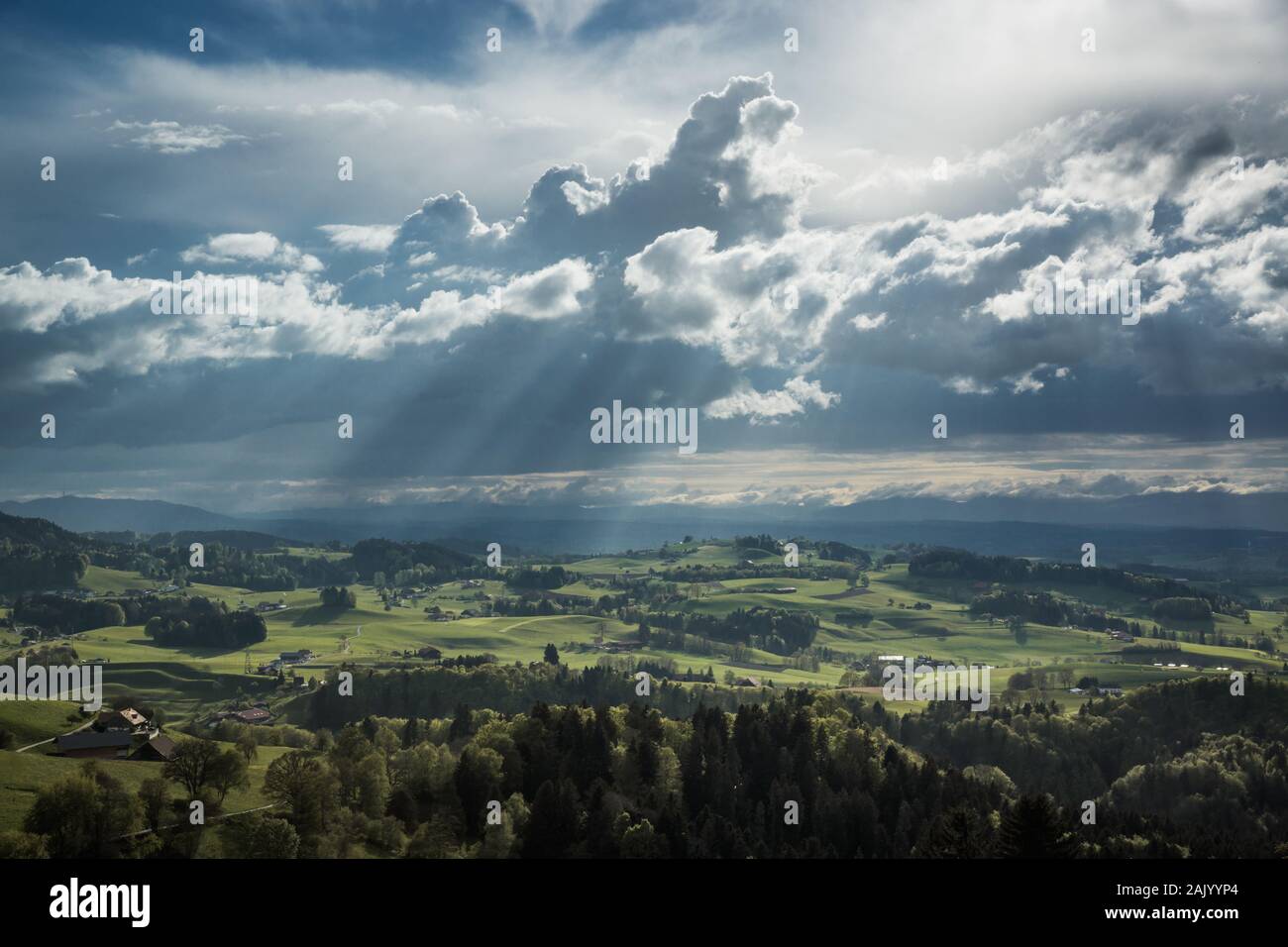 Colline e villaggi in Svizzera sotto un cielo nuvoloso e raggi solari Foto Stock