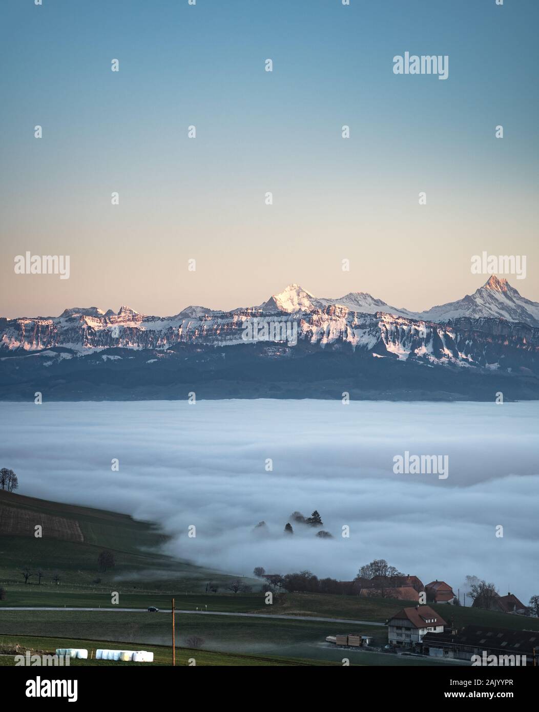 Swiss Mountain Range in Svizzera mentre la valle è coperta di nebbia durante il tramonto, super calda luce e cielo chiaro Foto Stock