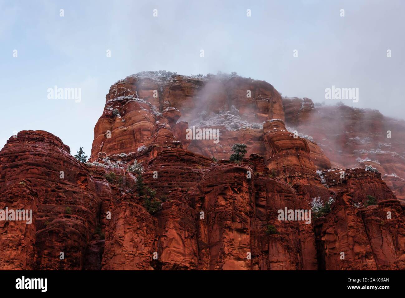 La nebbia e la nebbia che salgono dal Sedona Red Rock Mountains e scogliere in un freddo inverno mattina con cielo nuvoloso. Foto Stock