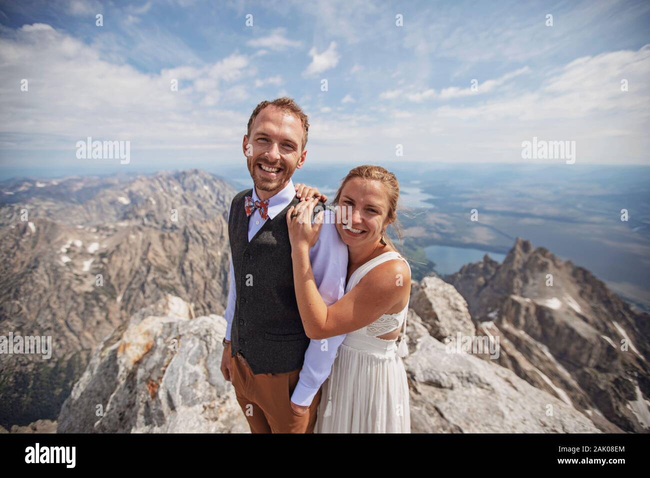 Felice sposa e scrigata sorridono sulla cima della montagna dopo essersi sposati Foto Stock