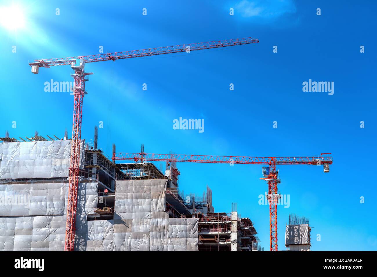 Un sacco di torre sito in costruzione di gru ed edificio con cielo blu sullo sfondo. Foto Stock