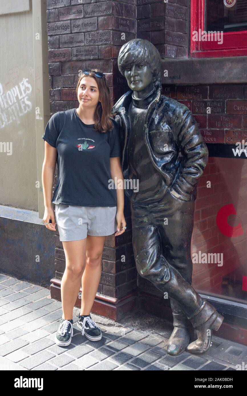 Donna turistica in posa da John Lennon statua, Cavern Quarter, Mathew Street, Liverpool, Merseyside England, Regno Unito Foto Stock