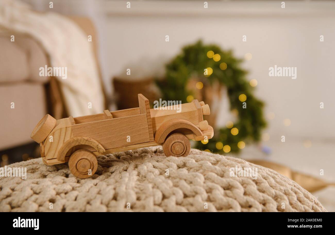 Bambini in legno di auto su una maglia ottoman contro lo sfondo di una corona di fiori da un albero di Natale con una ghirlanda di fiori accanto al divano Foto Stock