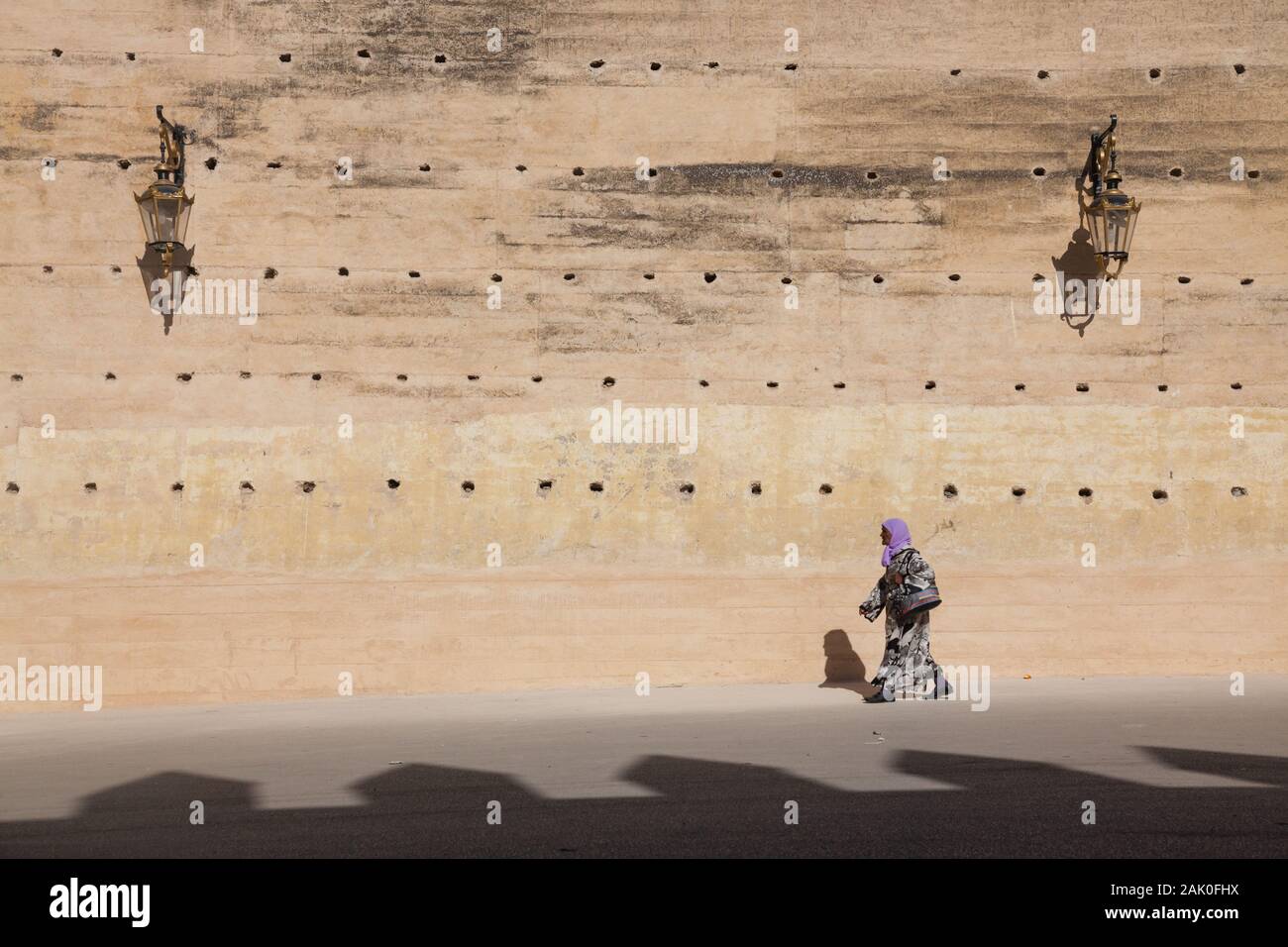 Lone donna in velo la sacca di custodia nel pomeriggio scenario di terra sbattuta le mura della città nella zona di Bab Mechouar e Bab Dekkakin in Fes (fez), Marocco Foto Stock
