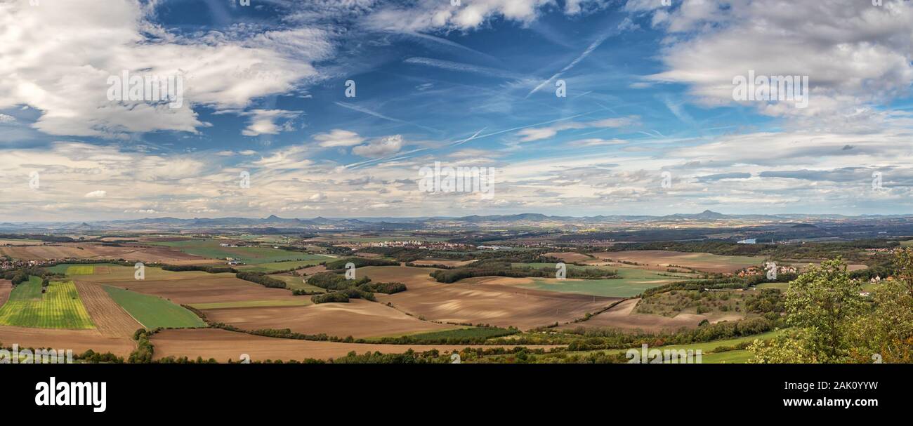 Paesaggio rurale con villaggi, campi e montagne sullo sfondo, cielo blu con nuvole bianche, vista dal monte RIP, Ceske stredohori, rappresentante ceco Foto Stock