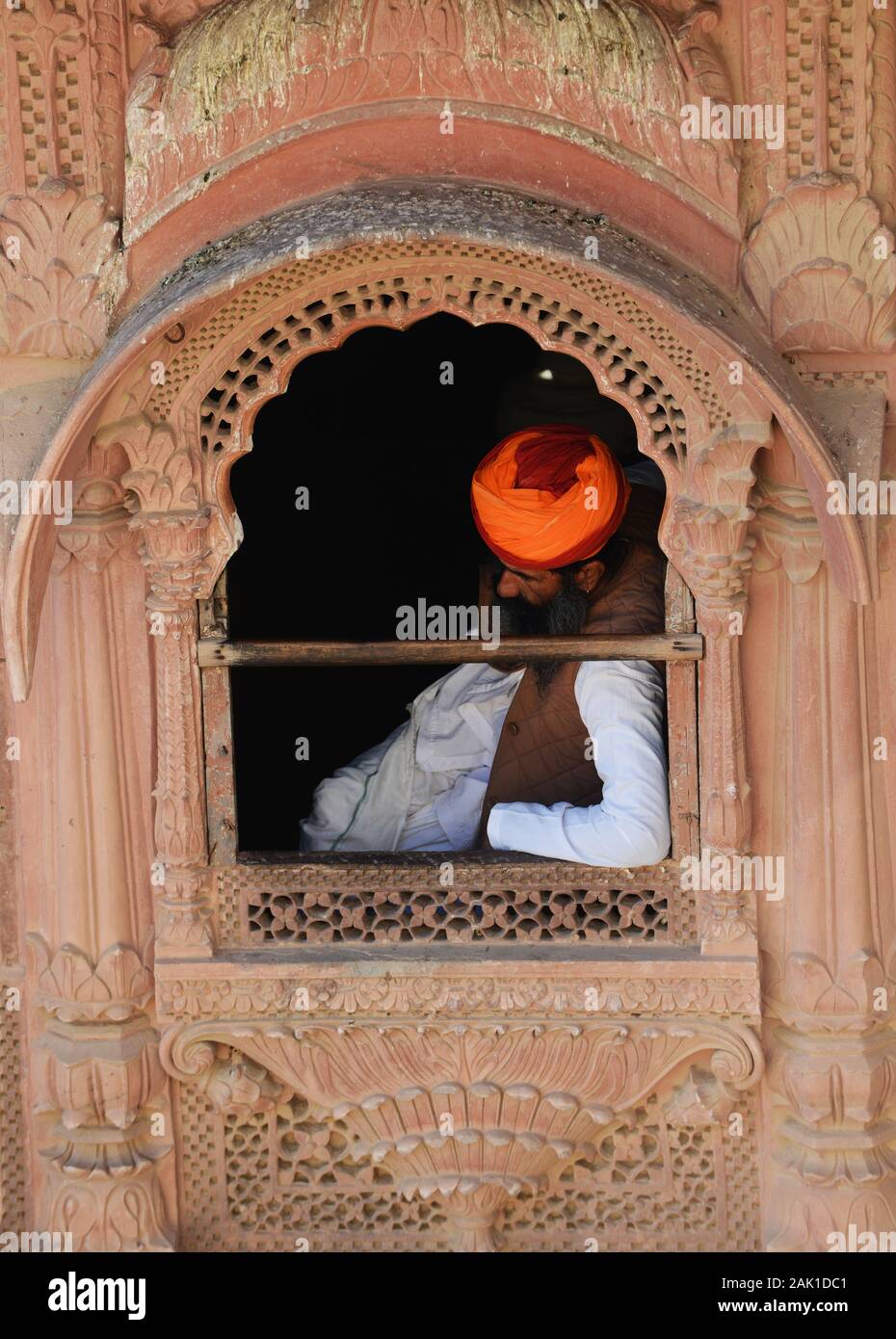 Un uomo di Rajasthani seduto da una finestra di palazzo al forte di mehrangarh in Jodhpur, India. Foto Stock
