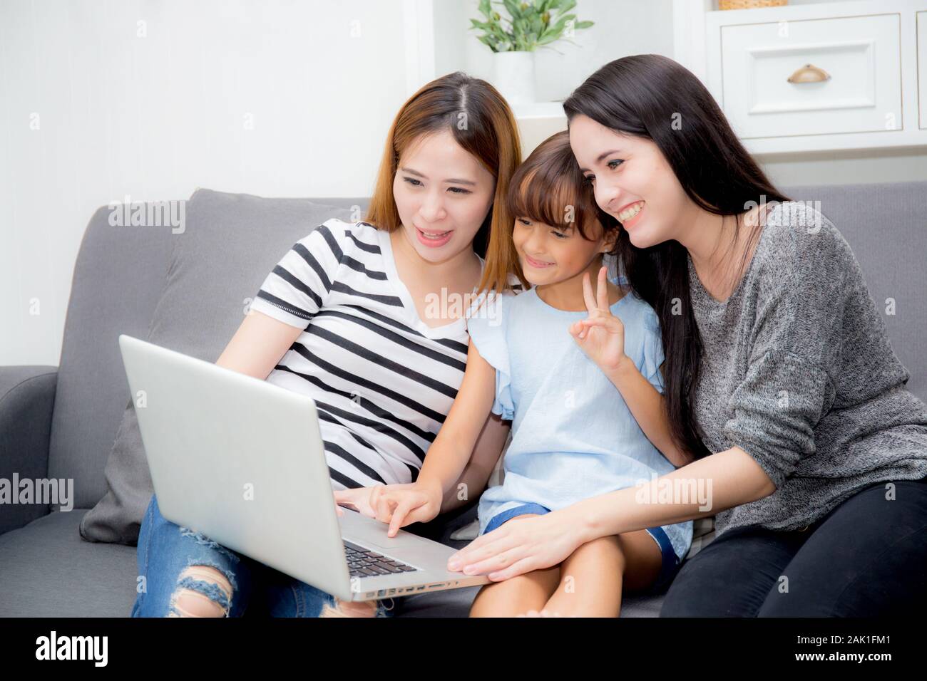 Madre, Zia e kid avente tempo insieme lerning con utilizzo portatile a casa sul lettino, il concetto di famiglia. Foto Stock