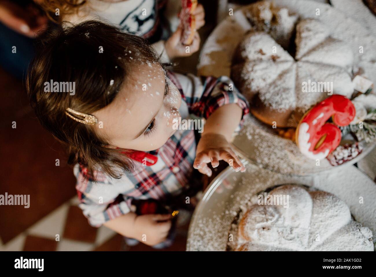 Bambina in cucina. Naso del bambino in farina. Festa di Natale in famiglia Foto Stock