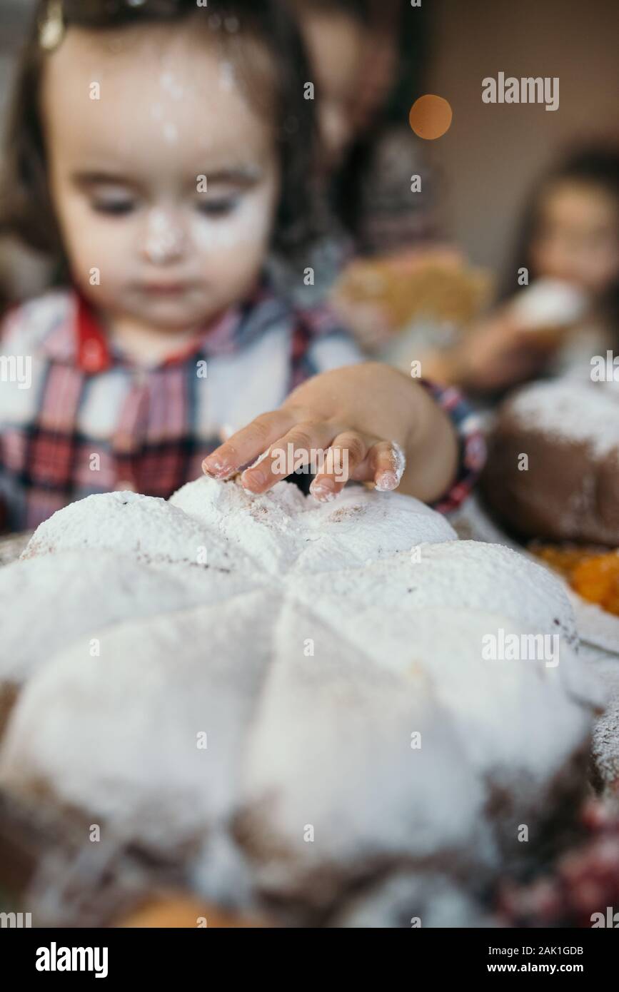 Bambina che tocca torta di Natale con le dita. Foto Stock