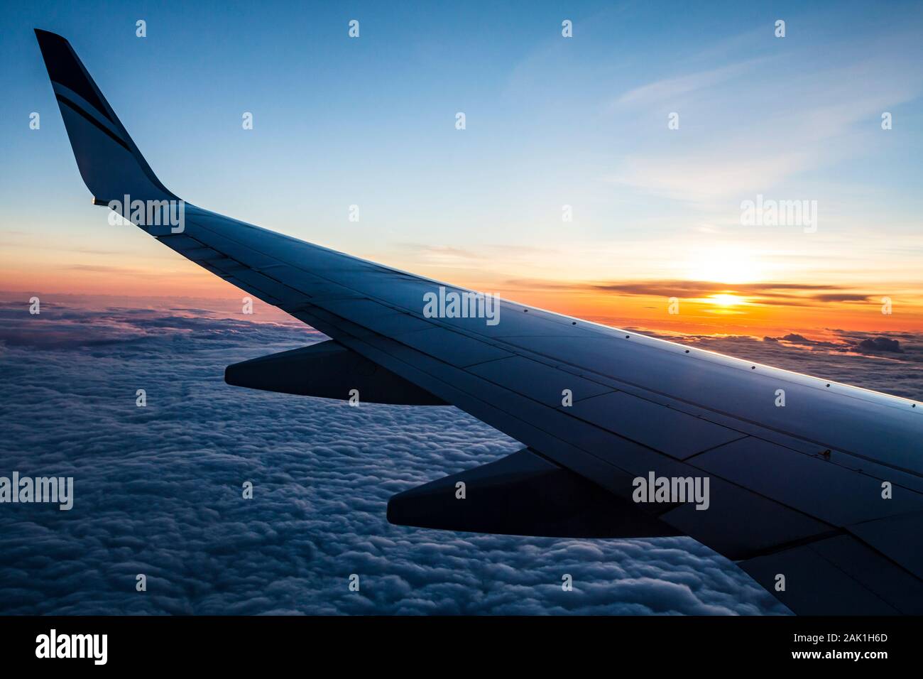 Guardando fuori all'ala di un jetliner come il sole tramonta. Foto Stock
