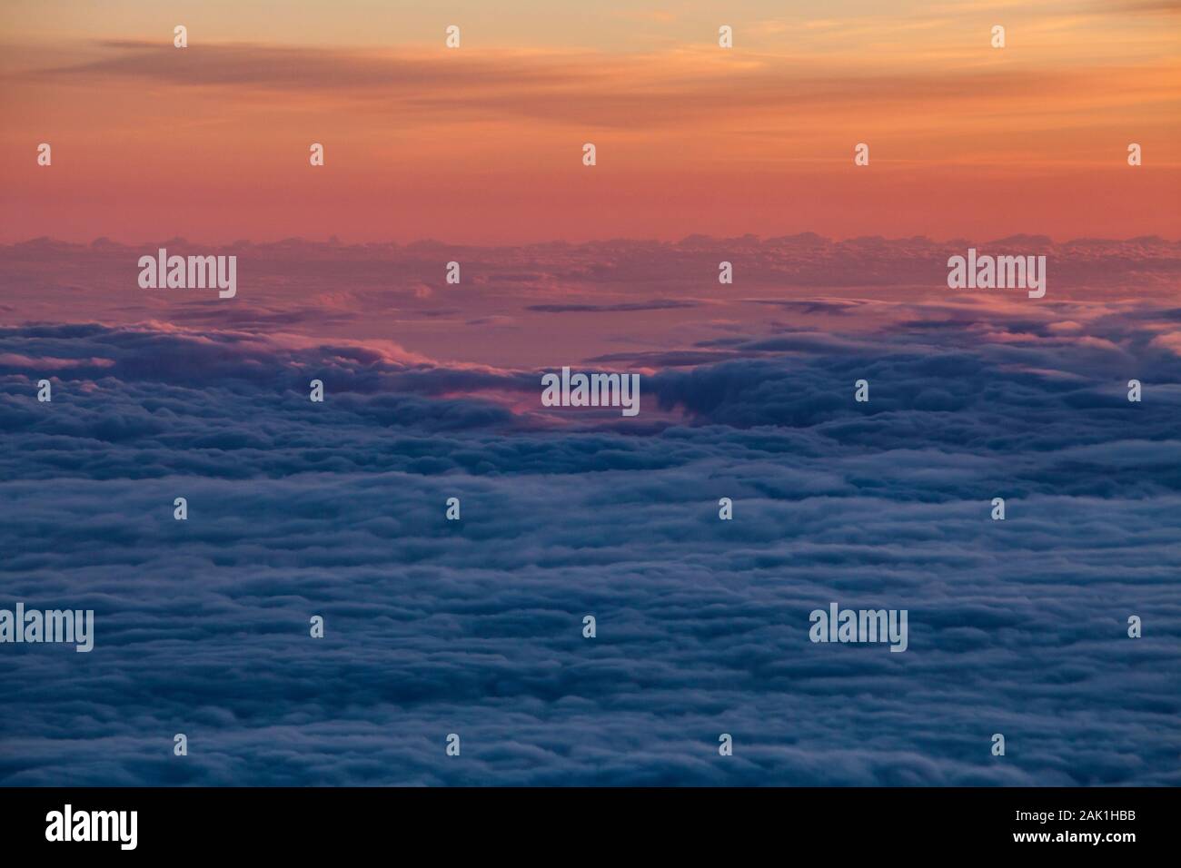 Una veduta aerea di gran lunga al di sopra delle nuvole al di sotto al tramonto. Foto Stock