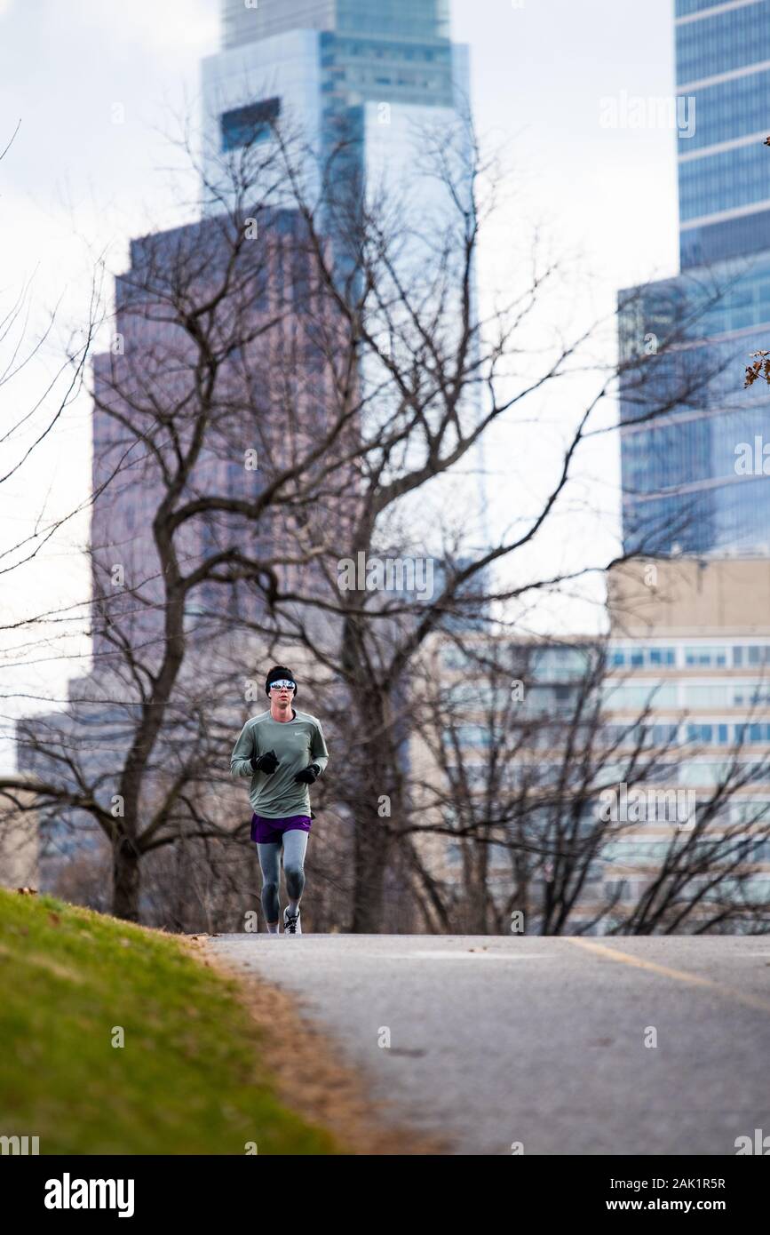 Un uomo che indossa abbigliamento da corsa invernale corre verso la  telecamera con il Comcast edificio in background Foto stock - Alamy