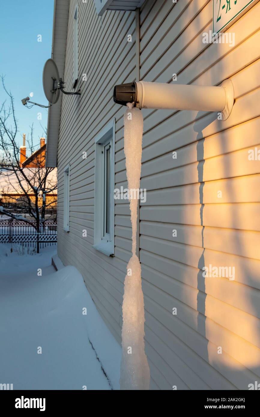 Il tubo di scarico della casa riscaldamento è ricoperta da ghiaccioli al suolo. Foto Stock
