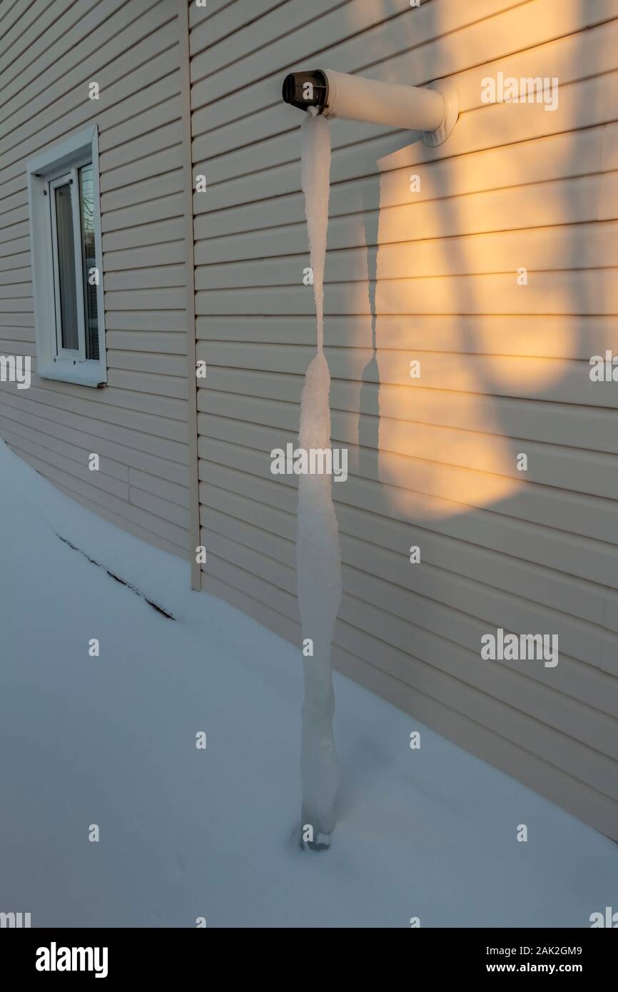 Il tubo di scarico della casa riscaldamento è ricoperta da ghiaccioli al suolo. Foto Stock