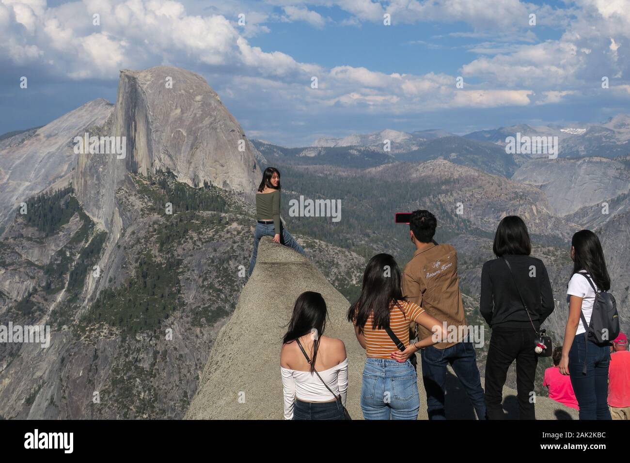 Ragazza turistica che posa per una foto con gruppo di amici ammirando Half Dome Foto Stock