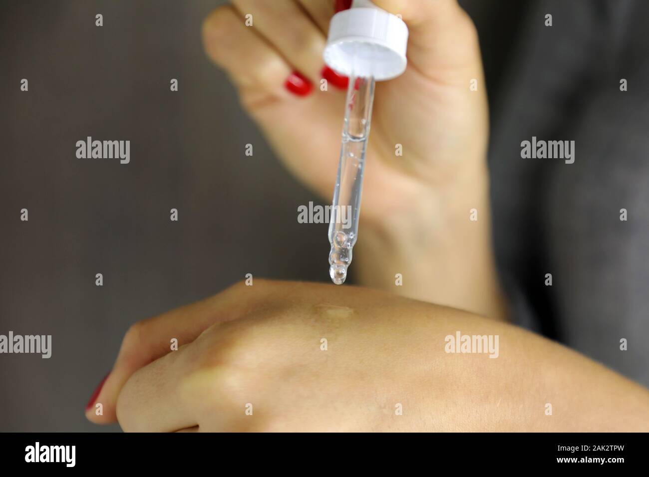 Mani femminili la caduta di siero idratante collagene. Protettore della pelle trattamento viso essenza olio, vitamina C. La bellezza health care cosmetici concetto. Foto Stock