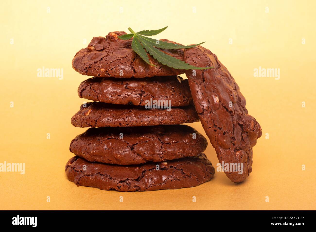 La cannabis cookie e foglia verde. cioccolato cookie di arachidi con la marijuana olio su uno sfondo giallo. Foto Stock