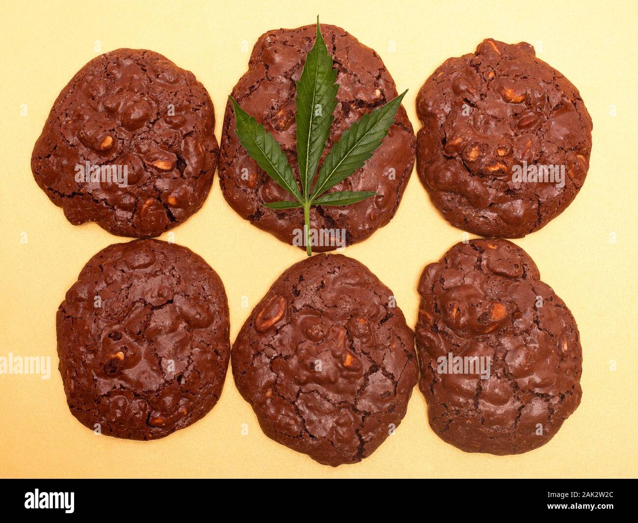 La cannabis cookie e foglia verde. cioccolato cookie di arachidi con la marijuana olio su uno sfondo giallo. Foto Stock