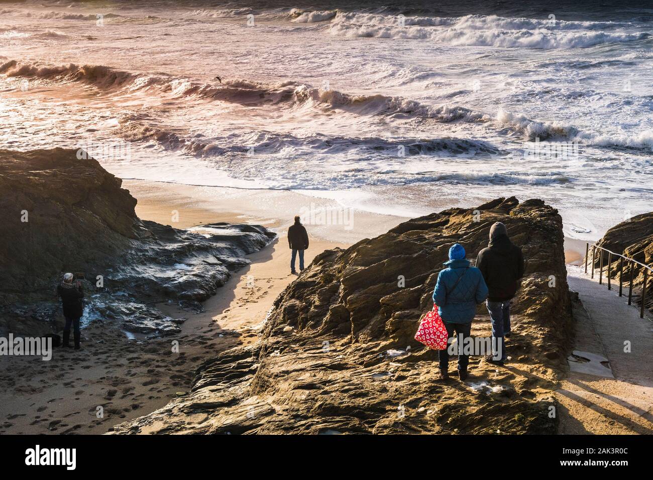 La gente a guardare le onde in arrivo in un mare increspato a poco Fistral a Newquay in Cornovaglia. Foto Stock