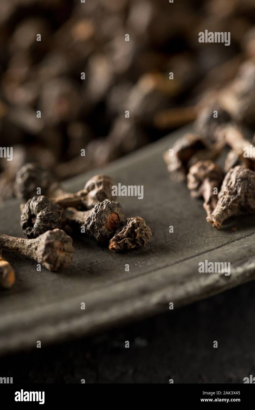 Cumulo di materie, essiccato cannella dei boccioli spice sulla piastra metallica sul rustico tavolo nero lo sfondo con il fuoco selettivo Foto Stock