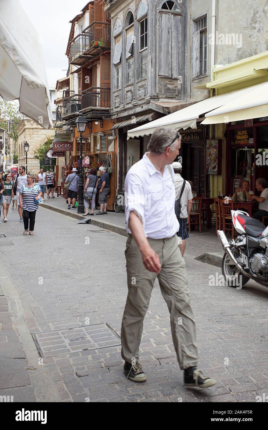 Maschio caucasico guardando sopra la sua spalla come egli cammina lungo una strada nella città vecchia di Rethymnon sull isola di Creta. Foto Stock