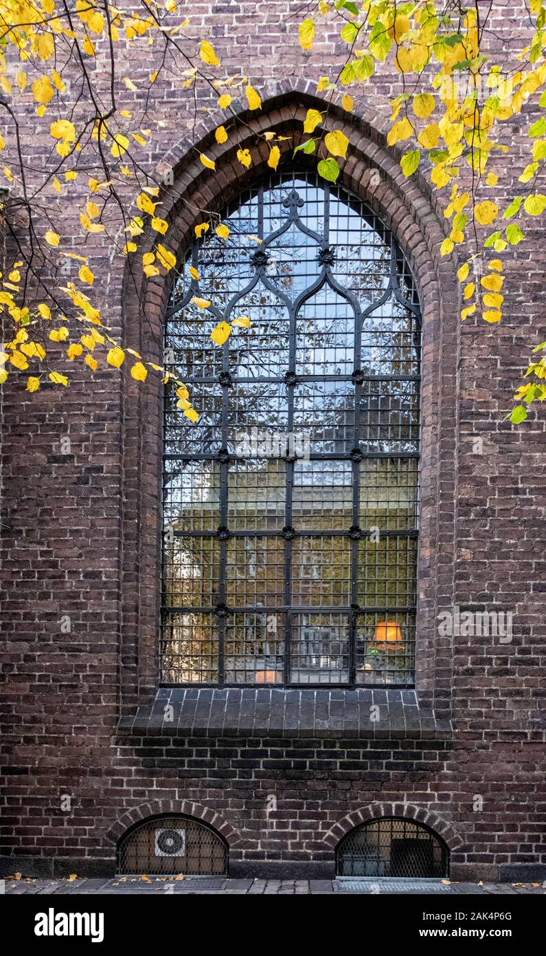 Copenaghen, Nikolaj chiesa edificio dettaglio.finestra ad arco,parete di mattoni gialli e foglie di autunno Foto Stock